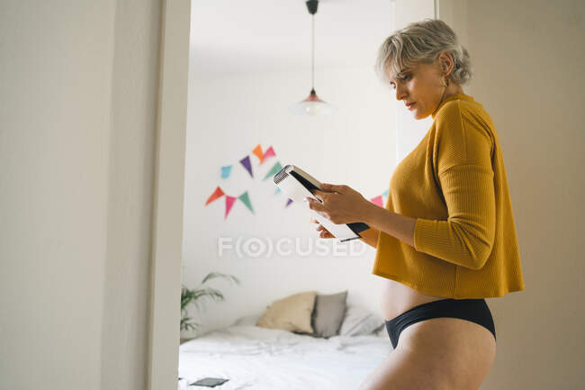 Frau steht zu Hause im Schlafzimmer und hält Notizblock — Stockfoto