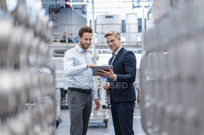 Two businessmen with tablet talking in a modern factory — Stock Photo