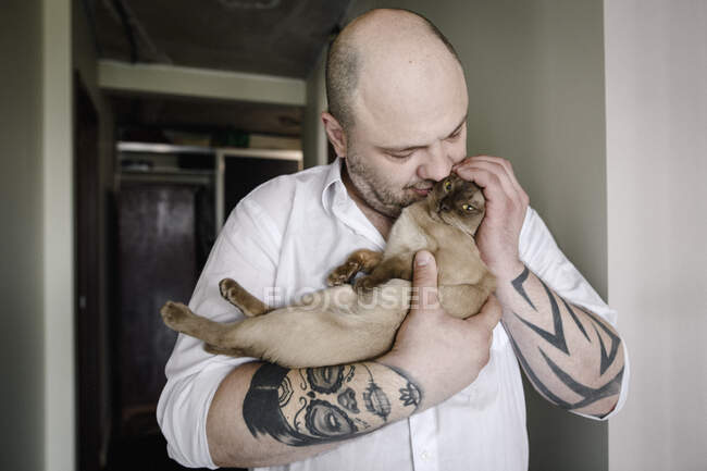 Tatuato uomo coccole con gatto birmano — Foto stock