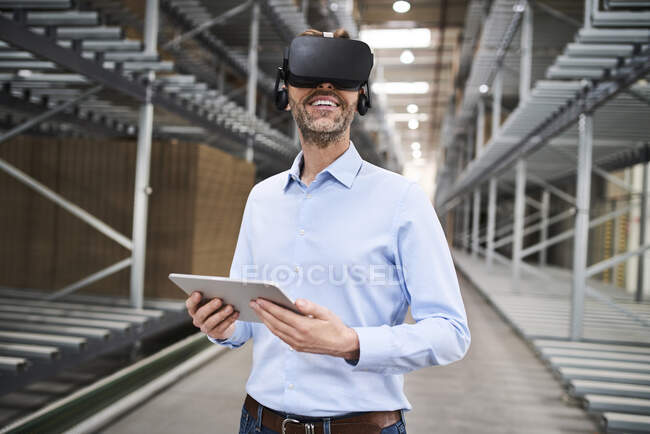 Businessman with tablet wearing VR glasses in factory — Stock Photo