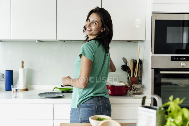 Portrait of smiling woman cooking in kitchen — Stock Photo