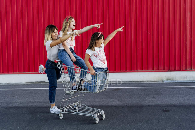 Mother and her daughters with shopping cart — Stock Photo