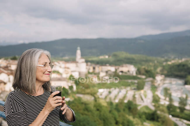 Mulher idosa relaxada com um copo de café em seu terraço, Belluno, Itália — Fotografia de Stock