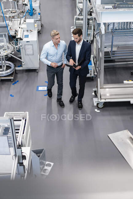 Dois empresários com prancheta conversando em uma fábrica — Fotografia de Stock