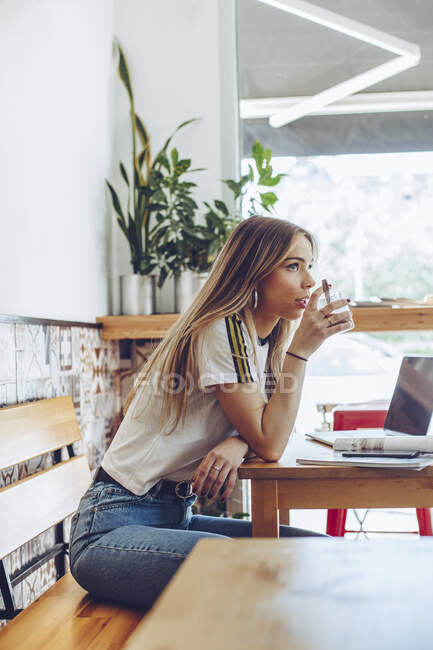 Mujer joven bebiendo café en la cafetería - foto de stock