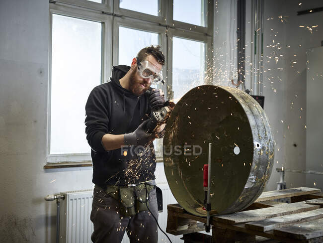 Mann arbeitet mit Schleifer an Metallbehälter — Stockfoto