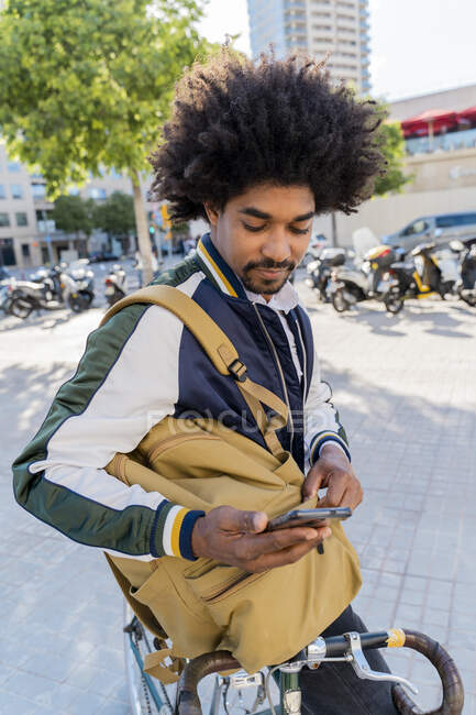 Hombre de negocios casual con bicicleta usando celular en la ciudad, Barcelona, España - foto de stock
