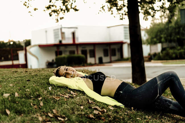 Sporty woman relaxing on grass after workout — Stock Photo