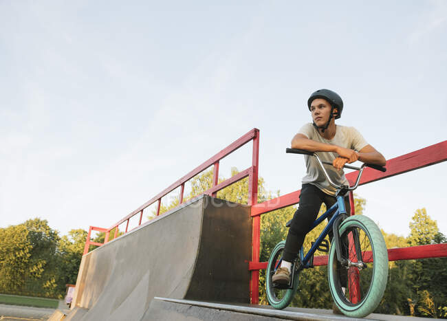 Молодой человек с велосипедом BMX в скейтпарке отдыхает — стоковое фото