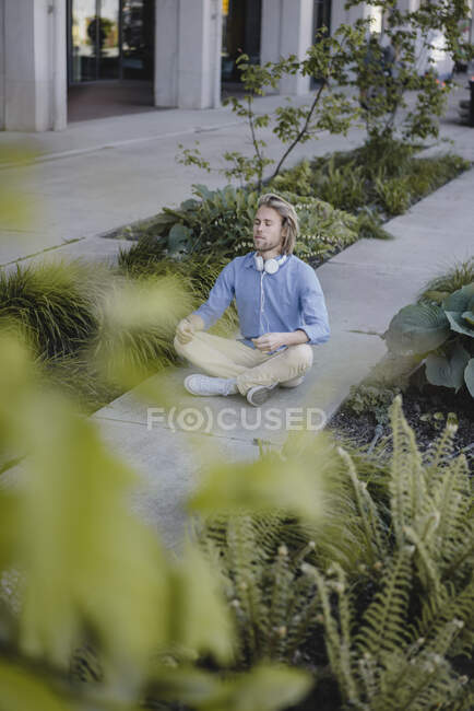 Jeune homme méditant devant un immeuble de bureaux — Photo de stock