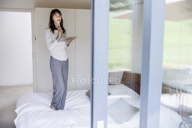 Frau steht zu Hause mit Tablet im Bett — Stockfoto