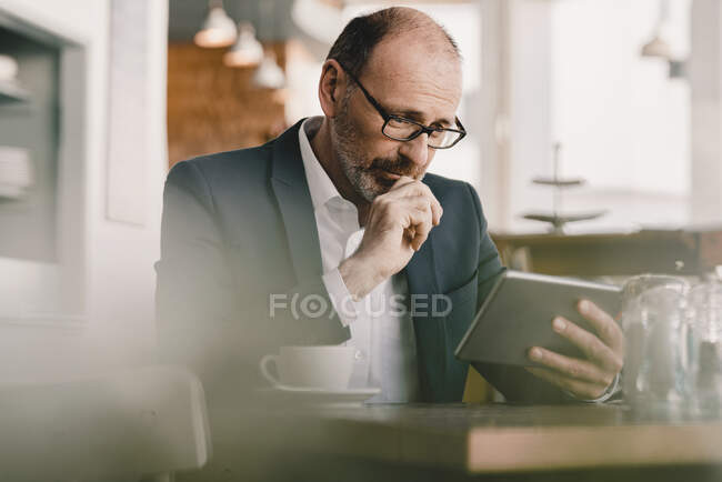 Дозрілий бізнесмен у кафе користується планшетом. — стокове фото