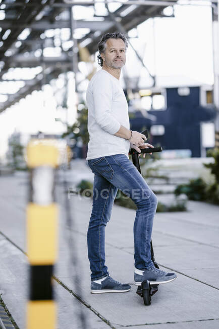 Зрілий чоловік зі смартфоном і електричним скутером. — стокове фото
