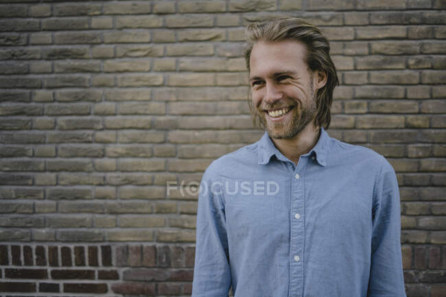 Ritratto di un giovane sorridente davanti a un muro di mattoni — Foto stock