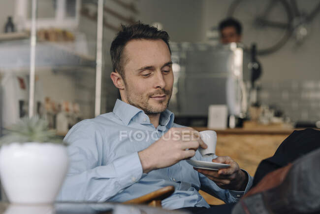 Successful businessman sitting in coffee shop, drinking coffee — Stock Photo