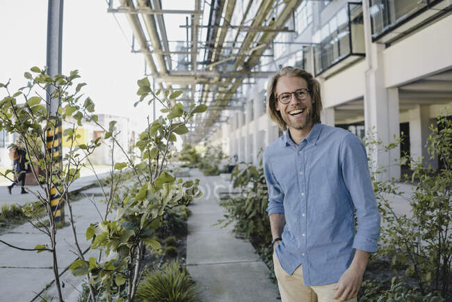 Happy young man standing on pavement surrounded by plants — Stock Photo