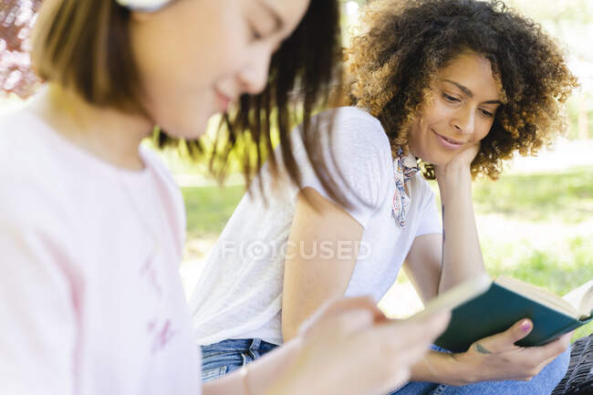 Donna sorridente con libro rilassante nel parco — Foto stock