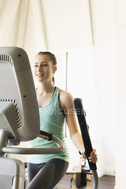 Mujer joven haciendo ejercicio en la máquina de paso en el gimnasio de fitness - foto de stock