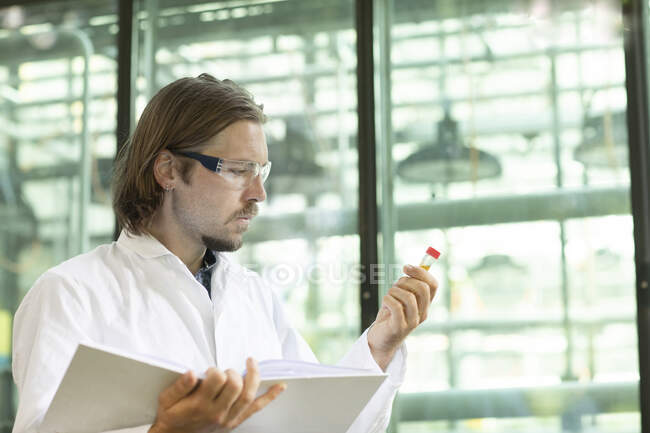 Investigador en una capa de laboratorio examinando plantas en un invernadero - foto de stock