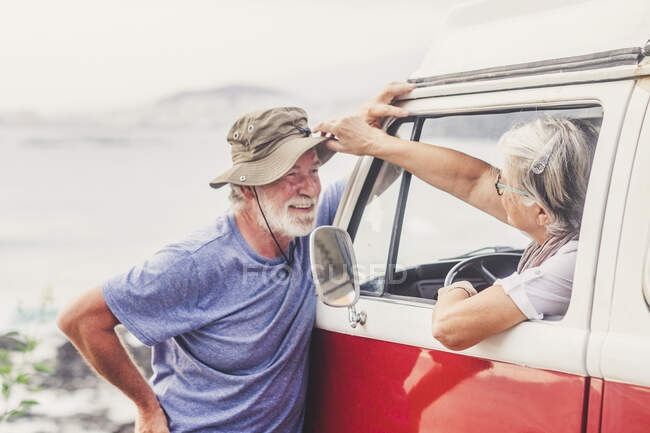 Старшая пара путешествует в винтажном фургоне, отдыхает у моря, разговаривает — стоковое фото