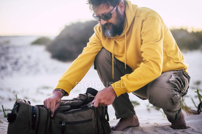 Людина з жовтим светром і коричневий кошик на пляжі. — стокове фото