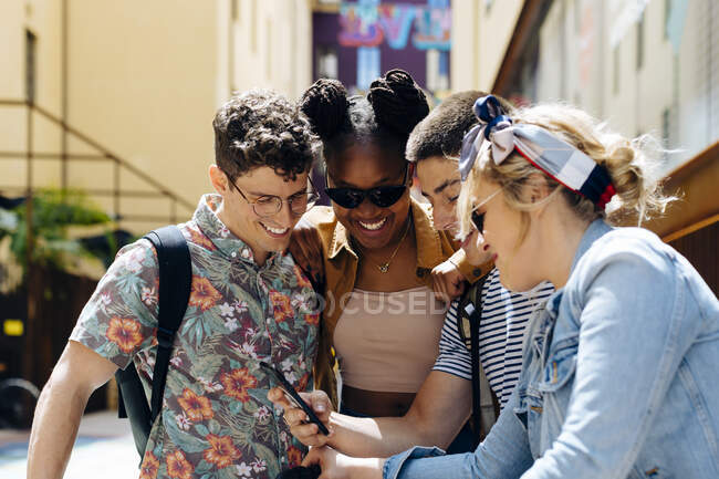 Étudiants se réunissant dans une arrière-cour, parler, débrancher les smartphones — Photo de stock
