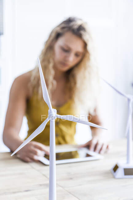 Modelo de turbina eólica y mujer con tableta digital en segundo plano en una oficina - foto de stock