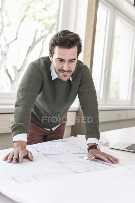 Jeune architecte travaillant sur un plan dans un bureau lumineux — Photo de stock