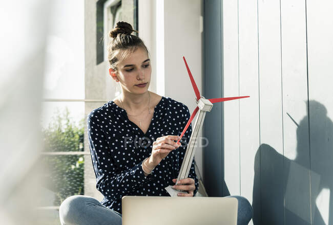 Молодая женщина дома держит модель ветряной турбины — стоковое фото