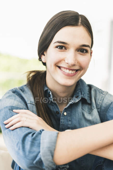 Retrato de una joven sonriente con camisa de mezclilla en casa - foto de stock