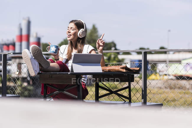 Молодая женщина отдыхает в пивном саду с наушниками и планшетом — стоковое фото