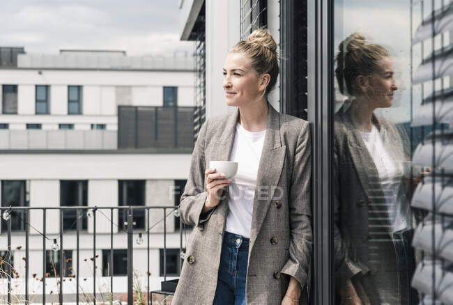 Femme d'affaires avec tasse de café debout sur la terrasse du toit — Photo de stock