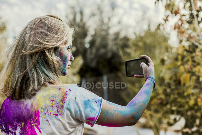 Girl Holi powder colors in her face, taking selfie, Germany — Stock Photo