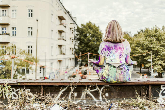 Chica con colores Holi en su ropa sentada en el puente, Alemania — mujer  joven, aire libre - Stock Photo | #462602462