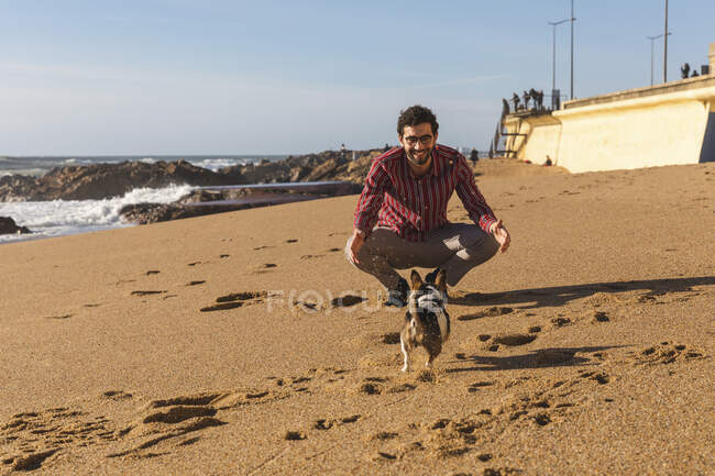 Portugal, Porto, young man playing on the beach with his dog — Stock Photo