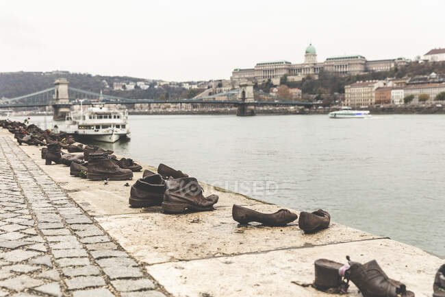 Sculture di scarpe Waterside, monumento alla Seconda Guerra Mondiale, con Ponte delle Catene e castello di Buda sullo sfondo, Budapest, Ungheria — Foto stock