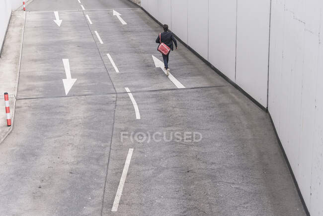 Visão traseira do empresário correndo na estrada com sinais de seta — Fotografia de Stock