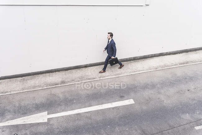 Geschäftsmann läuft mit Pfeilschild auf Straße — Stockfoto