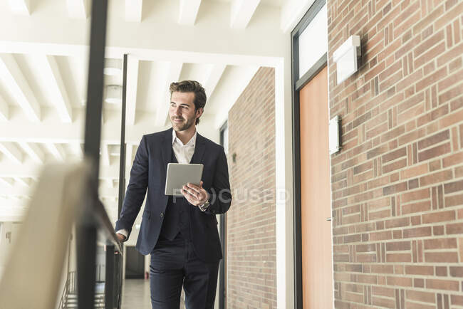 Giovane uomo d'affari in piedi sulla galleria in un moderno edificio per uffici, utilizzando tablet digitale — Foto stock