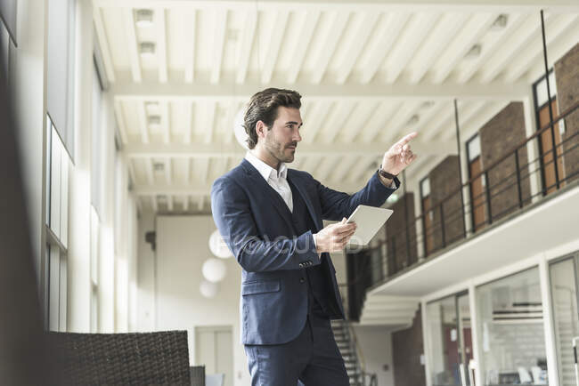 Manager di successo in piedi in un moderno edificio per uffici, utilizzando il computer portatile, puntando — Foto stock