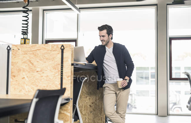 Giovane uomo d'affari in ufficio moderno, utilizzando il computer portatile sulla scrivania alta — Foto stock