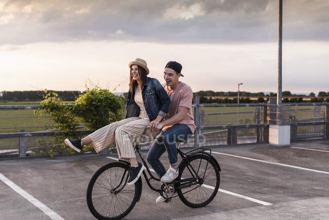 Felice giovane coppia insieme su una bicicletta sul ponte di parcheggio — Foto stock