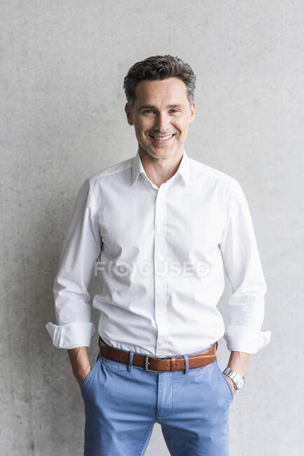 Бізнесмен у білій сорочці з сірою стіною на задньому плані. — стокове фото
