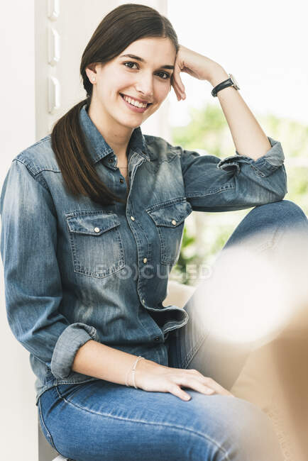 Porträt einer lächelnden jungen Frau im Jeanshemd zu Hause — Stockfoto