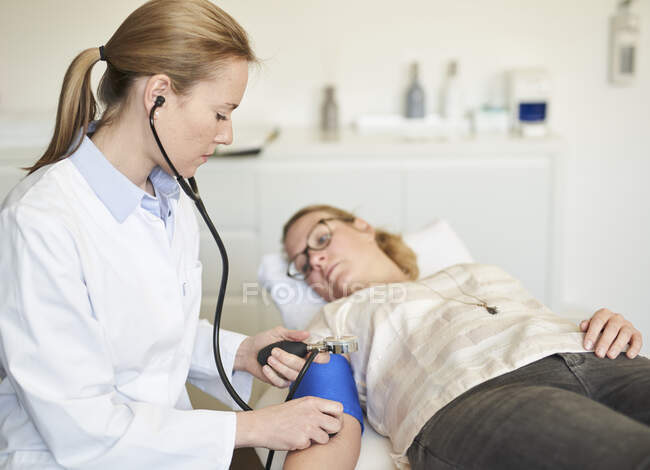Medico donna che prende la pressione sanguigna del paziente nella pratica medica — Foto stock