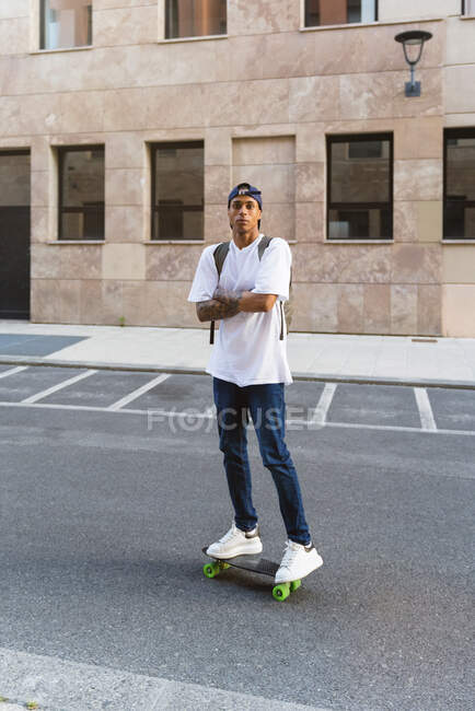 Ritratto di giovane tatuato in piedi su skateboard — Foto stock