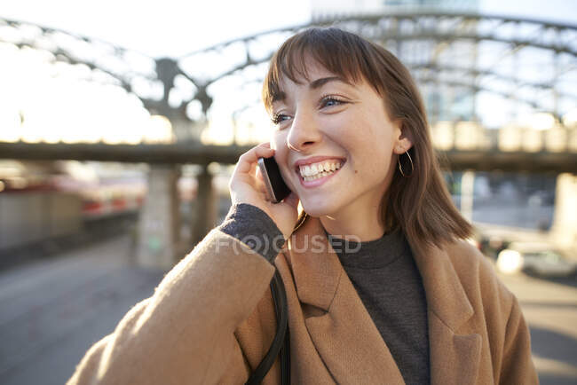 Portrait de jeune femme d'affaires heureuse au téléphone en plein air — Photo de stock