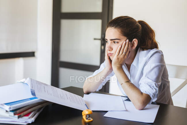 Frustrierte Studentin mit Dokumenten am Schreibtisch zu Hause — Stockfoto