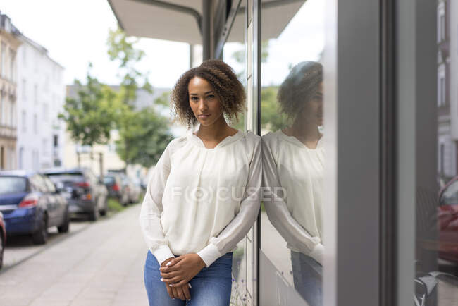 Portrait de jeune femme appuyé contre la vitrine — Photo de stock