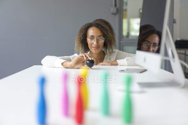 Portrait de jeune pigiste souriant jouant avec des broches miniatures sur le bureau — Photo de stock